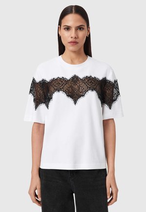 White cotton t-shirt featuring a scalloped black lace panel across the chest, with short sleeves and a relaxed fit.