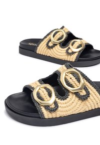 Sandali intrecciati in paglia con due fibbie dorate, rifiniture nere e una suola testurizzata. Combinazione di colori beige chiaro e grigio scuro.