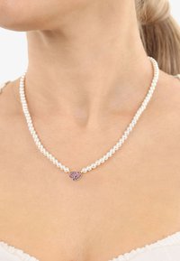 Collana di perle con perle bianche rotonde, un accento centrale in oro con pietre preziose viola, che mostra una texture liscia e un design classico.