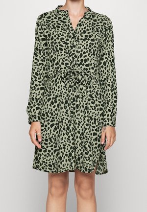 Sukienka o długości do kolan, z długimi rękawami w oliwkowej zieleni z czarnym wzorem pantery, posiadająca kołnierz i wiązanie w talii.