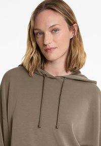 Khaki hooded sweatshirt with a relaxed fit, textured fabric, and adjustable drawstring accents. Features a simple, minimalist design.