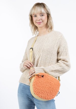 Borsa rotonda con un davanti in tessuto arancione morbido e un retro in pelle gialla liscia. Presenta un accentuato in catena e una tracolla regolabile.