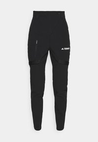 Pantalones exteriores negros con un diseño elegante, cintura elástica, dos bolsillos con cremallera y un logo de marca en el muslo.