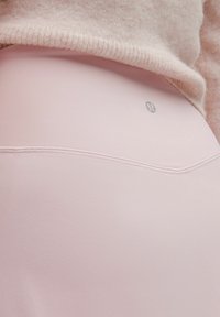 Roze tajice od rastezljivog materijala, s glatkom teksturom i malim logotipom straga, s vidljivim šavovima.