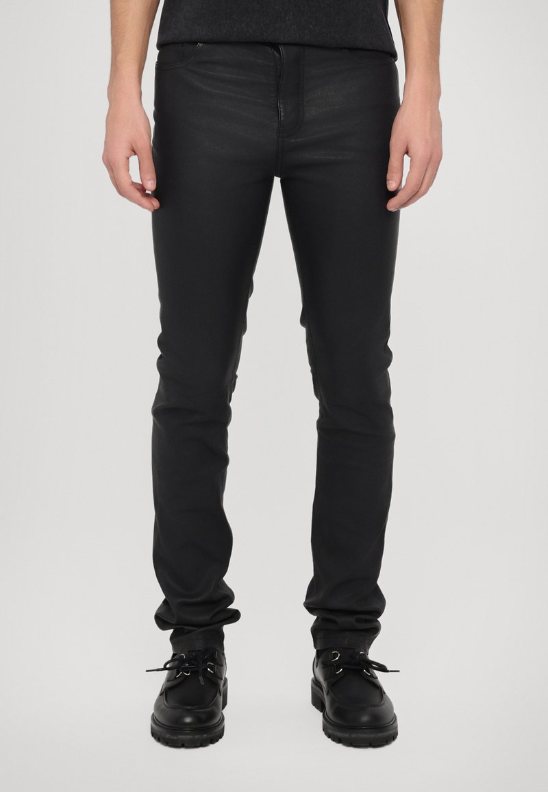Zwarte skinny jeans van glad, rekbaar materiaal; voorzien van voorkruiden, riemlussen en een strakke pasvorm voor een gestroomlijnde uitstraling.