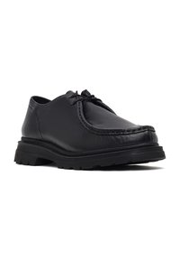 Chaussure noire en cuir à lacets avec semelle épaisse en caoutchouc et détails cousus, conçue pour un usage décontracté ou formel.