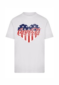 White t-shirt featuring a heart design with red and white stripes, and blue background with white stars, incorporating the Coca-Cola logo.