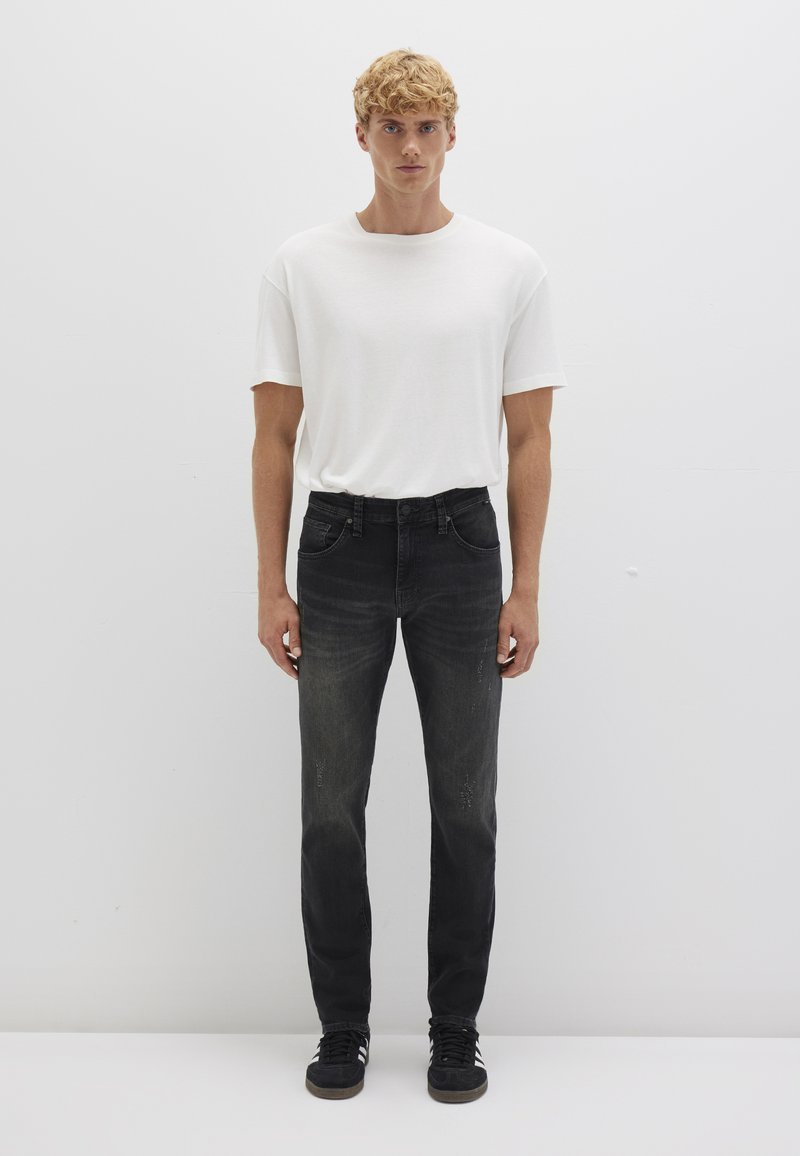 White cotton t-shirt, black denim jeans with slight fading, and black sneakers. Simple design, relaxed fit, minimal detailing.