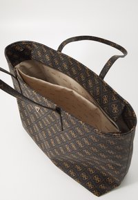 Black tote bag with gold logo pattern, synthetic material, open top, two handles, beige interior lining with logo print, and zippered compartment.