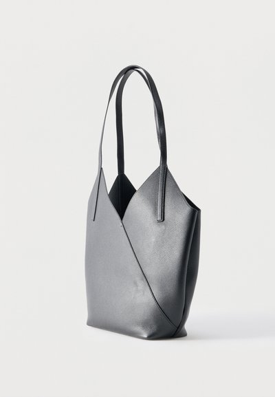 Μαύρη δερμάτινη τσάντα ώμου με δύο μακριές λαβές και ένα δομημένο, γεωμετρικό σχέδιο σε ουδέτερο φόντο.