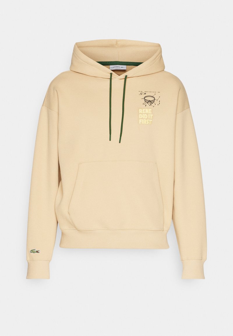 Beige hoodie met voorknopzak, groene trekkoorden, tekst "RENE DID IT FIRST", technische tekening op de borst en klein groen krokodil-logo op de mouw.