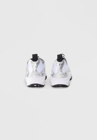 Bakside av metallisk sølv- og hvite sneakers med svarte detaljer, som har en teksturert overdel, polstret krage og en slitesterk hvit såle.