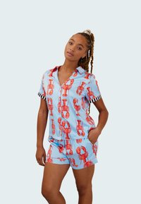 Conjunto de pijama corto con estampado de langostas en azul claro, hecho de un material similar a la seda que presenta acentos en las mangas a rayas negras y blancas.