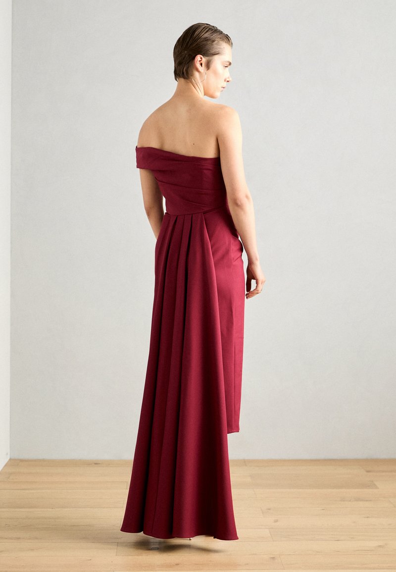 Rochie burgundy cu umeri goi, fustă plisată, cu un corset fără cusături și material fluid. Textură netedă, design până la podea, hardware minim.