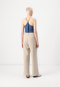 Denim backless top with adjustable straps, paired with high-waisted beige wide-leg trousers. Minimalist design, smooth texture, neutral colors.