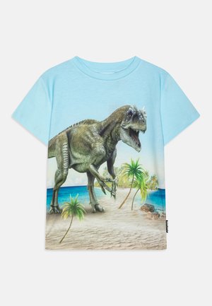 T-shirt azzurro chiaro a maniche corte con una grafica dettagliata di un dinosauro, palme e una scena di spiaggia stampata sul davanti.