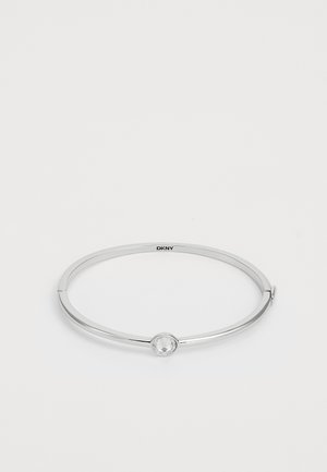 Sudraba apro, kurai ir gluda, apaļa forma un skaidrs, apaļš rotājums centrā, ar smalku aizdari.