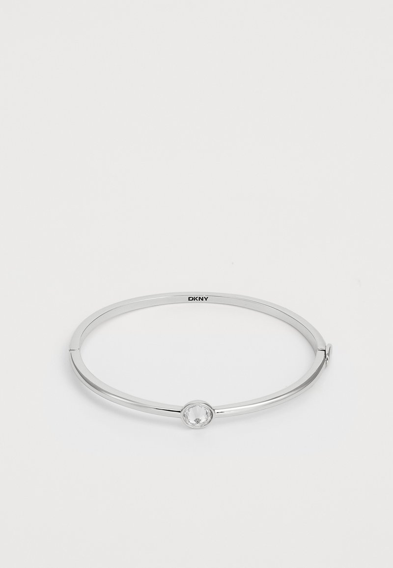 Pulseira de prata com um design liso e redondo, apresentando uma decoração redonda e clara no centro, com um mecanismo de fecho sutil.