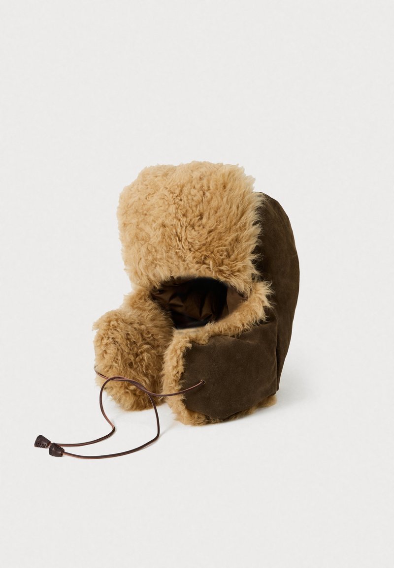 Manoplas de ante marrón forradas con un suave faux fur de color beige claro, con una cierre de cordón. Textura suave con forma redondeada y puño voluminoso.