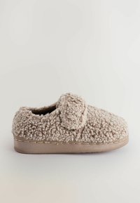 Beige tøffel lavet af blødt, tekstureret stof med en luksuriøs, langhåret overflade. Har et slip-on design og stikninger langs sålen.