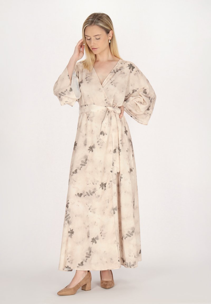 Rochie cu un design înveșmântat dintr-un material bej deschis cu un model floral pictat în acuarelă în nuanțe de gri. Are mâneci largi, un cordon la talie și o siluetă vaporoasă.