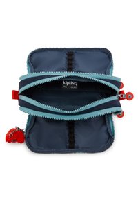 Borsetta Kipling in navy con dettagli blu chiaro. Due scomparti, tirazip rossi e un portachiavi peloso rosso attaccato. Tessuto testurizzato.