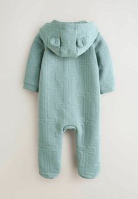 Lyseblå hættetrøje i et struktureret stof med et geometrisk mønster, som har en rund hætte og lange ærmer.