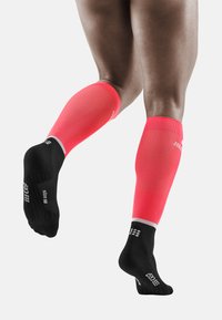 Calze compressive fino al ginocchio con una parte superiore di colore rosa brillante e una suola nera. Tessuto texturizzato con colori a contrasto e accenti del logo.