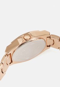 Rose gold metal armbåndsur med en hexagonal urskive, struktureret krone og en poleret sølv bagcover; sammenkoblet armbåndsstil og glat finish.