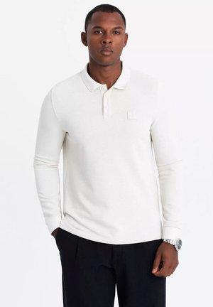 Camisa polo de manga larga en tejido blanco texturizado, con cuello, tapeta de tres botones y un pequeño logo en el pecho.