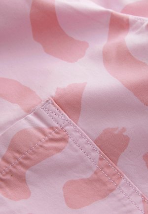 Rosa Stoff mit einem großen, abstrakten, hellrosa Muster, das sichtbare Nähte und eine umgeschlagene Kante aufweist. Weiche, glatte Textur.
