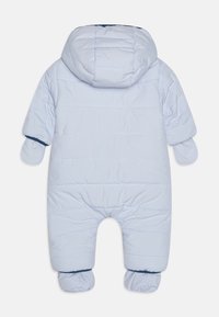 Jasnoniebieski śpioszek zimowy z kapturem, z pikowanym wzorem i elastycznymi mankietami. Zawiera przynitowane rękawiczki dla dodatkowego ciepła.