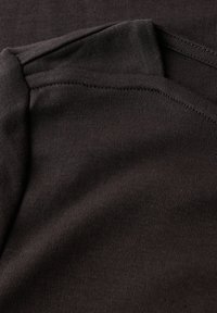 Primer plano de una tela marrón oscuro con costuras visibles y una textura de punto fino.