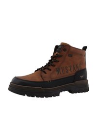 Botas de tobillo de cuero marrón con acentos de goma negra, diseño con cordones, suela resistente y la marca "MUSTANG" en el costado. Acabado texturizado.