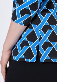 Maglietta maniche corte con un motivo geometrico di linee blu e bianche su uno sfondo nero, dotata di un dettaglio con spacco laterale all'orlo.