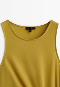 Tank top w kolorze musztardowym, wykonany z teksturowanej tkaniny, z okrągłym dekoltem i bez rękawów. Widoczna metka z marką i instrukcjami pielęgnacyjnymi.