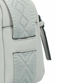 Bolso de cuero gris claro con una correa texturizada con un patrón geométrico, costuras en contraste y un brillo sutil en la superficie.