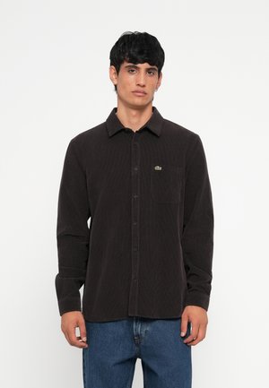 Dark brown corduroy shirt with a button-down collar, long sleeves, a chest pocket, and a small green logo accent.