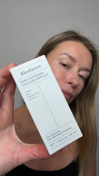 Kvinne som holder Biodance Pore Tightening Collagen Ampoule hudpleieproduktboks nær ansiktet.