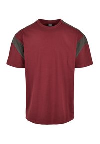 Camiseta burdeos de manga corta, con detalles en gris oscuro en los hombros. Confeccionada con un tejido suave y transpirable, de corte relajado.