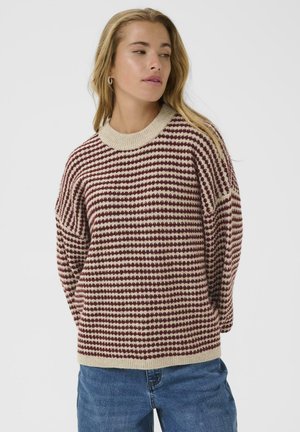 Maglione a maglia in crema e bordeaux, con un motivo a coda di rondine, collo rotondo a coste e vestibilità rilassata. Indossato con jeans di denim.