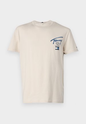 T-shirt in cotone beige con collo a giro, maniche corte e un logo blu nella zona sinistra del petto che presenta città e nome del marchio.