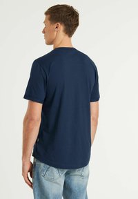 Marinblå bomullströja med korta ärmar, rund halsringning och rak nederkant. Inkluderar en liten logotypetikett på sömmen.