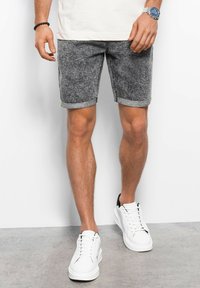 Grijze denim shorts met een opgevouwen zoom, voorzien van een groene accenten. Draagt met witte sneakers, die een casual, hedendaags ontwerp tonen.