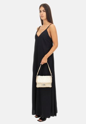Abito maxi senza maniche nero con scollatura a V profonda, abbinato a una borsa color crema e beige con dettagli in pelliccia e chiusura metallica.