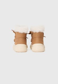 Bottes chevilles marron avec bordure en fausse fourrure, en suède doux, et une semelle en caoutchouc texturé. Comprend des lacets décoratifs et une fermeture éclair sur le côté.