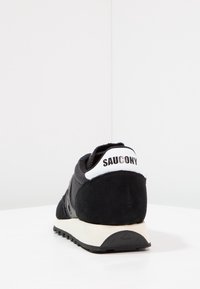 Czarne sneakersy z cholewką z zamszu i siateczki, z białym językiem pięty z napisem "SAUCONY" oraz kontrastującą białą podeszwą środkową.