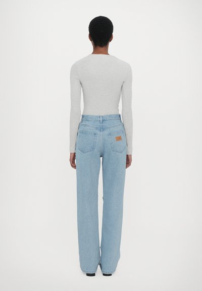 Jeans de perna larga azul claro feitos de denim, apresentando uma cintura alta, bolsos traseiros e um retângulo de couro rotulado na cinta.