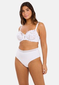 Bralette en dentelle blanche avec des bords festonnés et de délicats motifs floraux. Culottes blanches taille haute avec une ceinture en dentelle texturée.