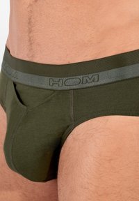 Olivově zelené slipy z měkké látky s šedým páskem s logem, klasického střihu a předním klínem pro podporu.